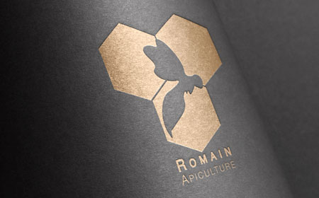Logo de la marque Romain Apiculture gaufré et doré sur fond noir